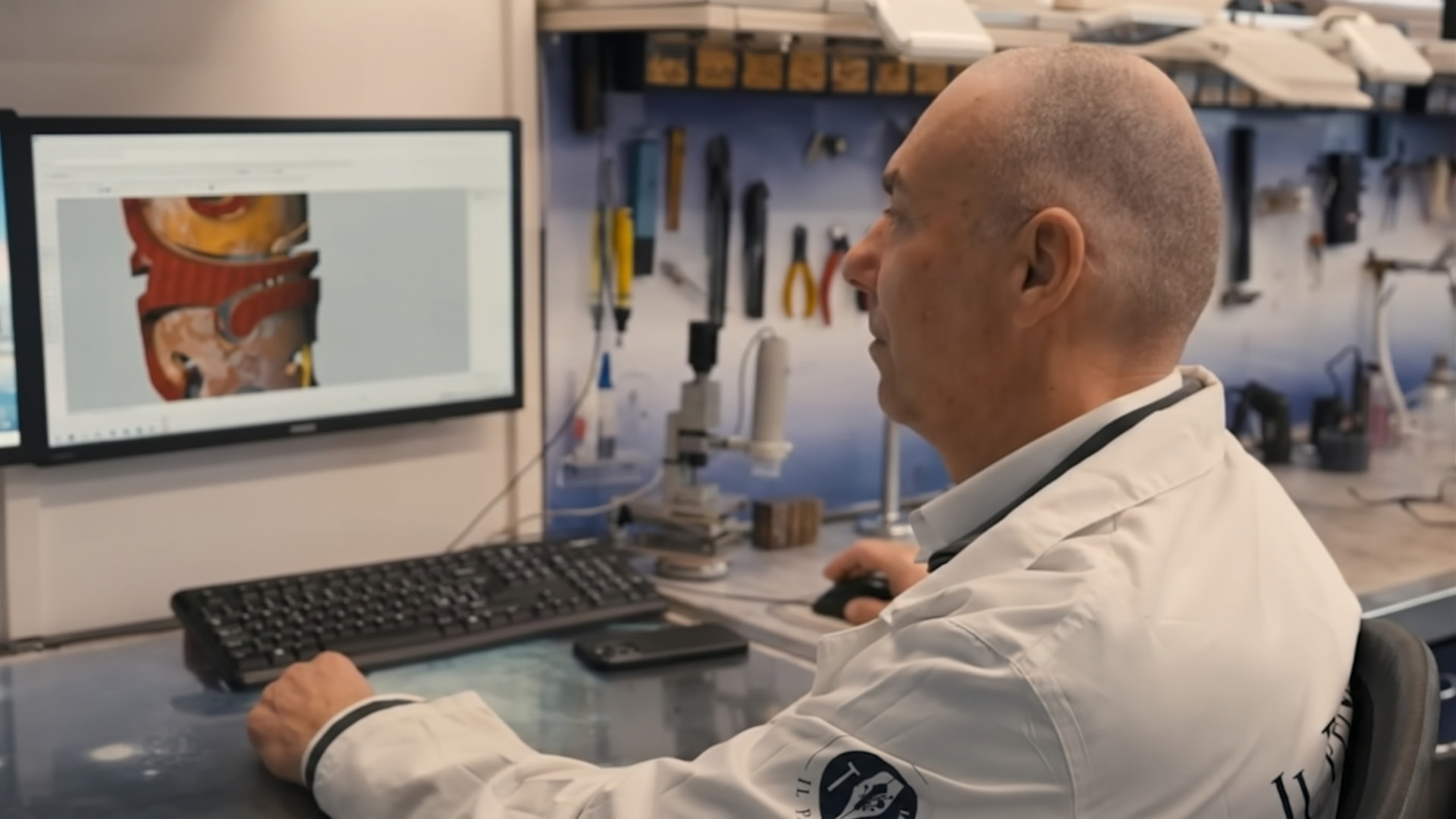 Fabio Moricci in camice bianco al lavoro al computer con il modello tridimensionale di una penna
